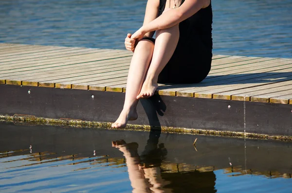 Young lady sitting on the jetty — Stock Photo, Image