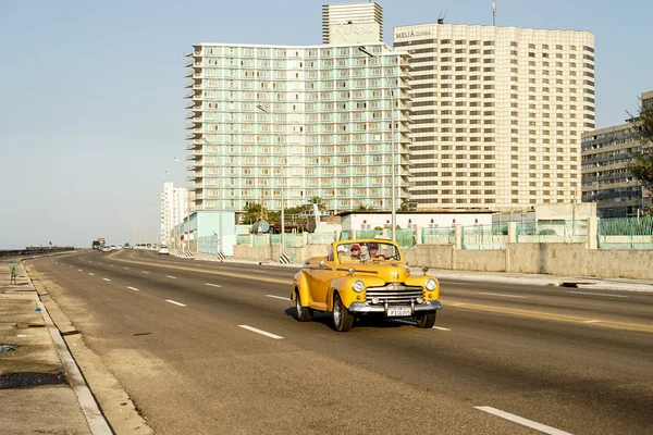 Yellow vintage american car in front of two Hotels — Stock Photo, Image