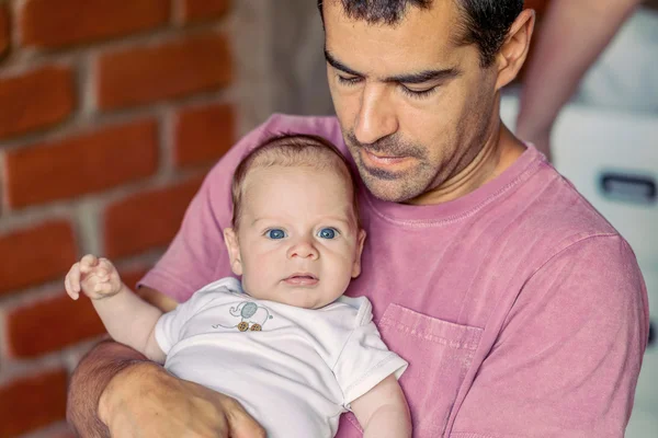Baban kolundaki güçlü mavi gözlü erkek bebek