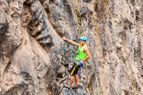 垂直方向の石壁を登る若いヒスパニック男 — ストック写真