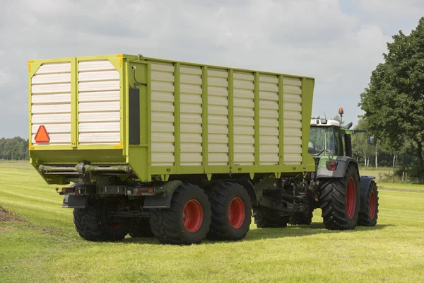 A levágott fű, a traktor és a rakodó kocsi szállítására — Stock Fotó