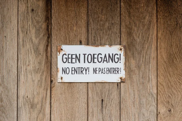 No Access sign in Dutch, English and French on a wooden door in the Netherlands