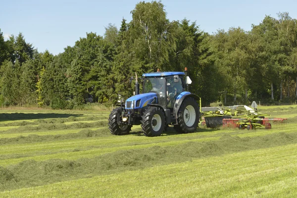 Vážně otřesena trávy s modrými traktoru — Stock fotografie