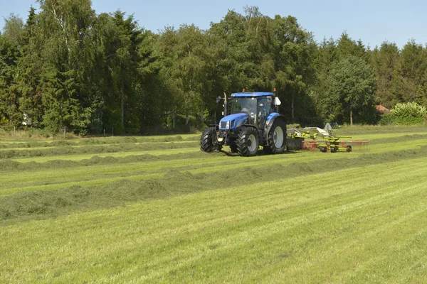 Vážně otřesena trávy s modrými traktoru — Stock fotografie