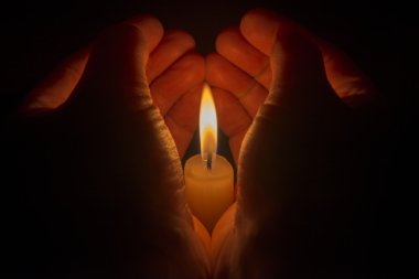 Yanan bir candl etrafında koruyucu eller