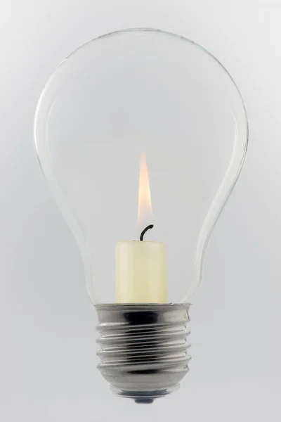 Концептуальная стеклянная лампочка с горящей свечой — стоковое фото