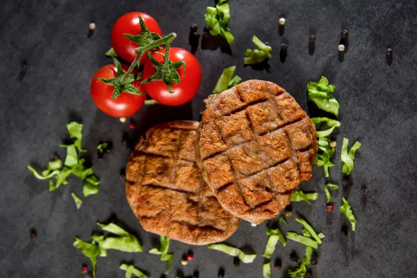 Tahta üzerinde taze hamburger pirzolası ve domates.