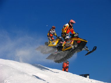 Duluth snocross yarışta bir tepenin üzerinde uçan Snocross yarışçılar.