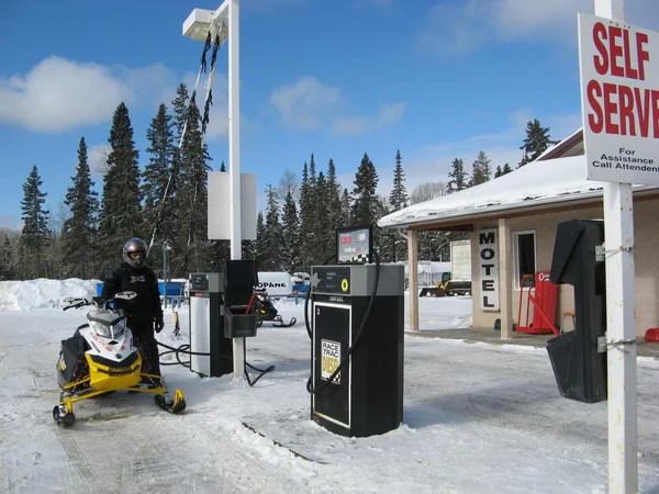 Snowmobiler fueling up a snowmobiles at a self-service gas station — Stock Photo, Image