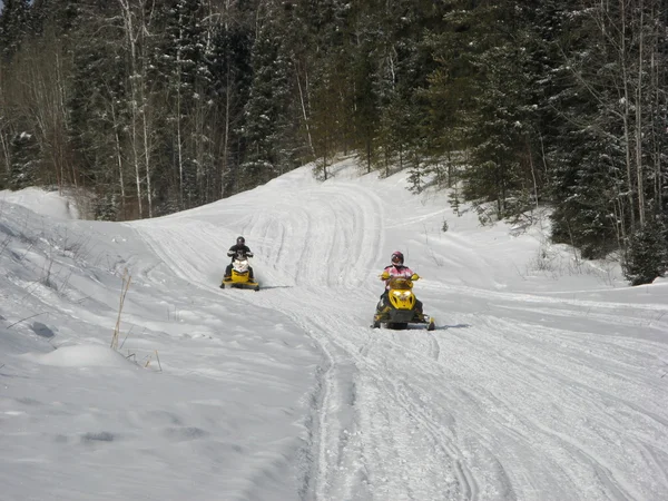 Two snowmobilers riding on a groomed snowmobile trail near Waskesiu in Central Saskatchewan. — Stock Photo, Image