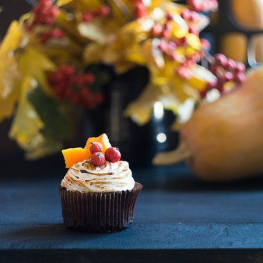 Kremalı balkabaklı kek, böğürtlen ve balkabağı parçalarıyla süslenmiş arka planda sonbahar yaprakları olan siyah ahşap masa. Seçici odak