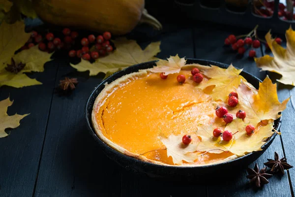 Geleneksel ev yapımı balkabağı turtası. Sonbahar yapraklarıyla süslenmiş. Koyu ahşap arka planda. Cadılar Bayramı ya da Şükran Günü bayramı yemeği.