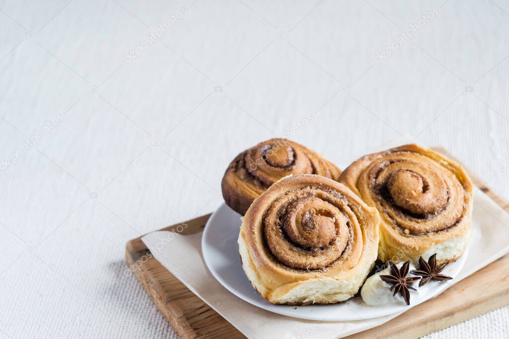 Cinnamon rolls. Homemade cinnamon buns on a plate on light rustic background, selective focus, copyspace.