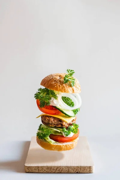 Pyszny Burger Latającymi Składnikami Szarym Tle Selektywne Skupienie — Zdjęcie stockowe