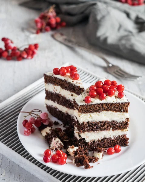 デザートだ 薄い背景に白いプレートの上に白いクリームと赤い果実とチョコレートビスケットケーキ 選択的焦点 — ストック写真