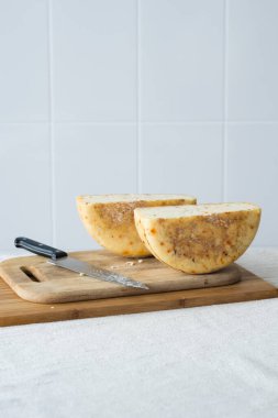 Ahşap bir tahtada kırmızı biberli dilimlenmiş organik peynir ve arka planda seramik fayans. Açık kırsal arka plan. Seçici odak.