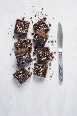 Bıçaklı çikolatalı kek kareleri, gri arkaplan, üst görünüm, dikey yönelim. Düz yerde yemek vardı.