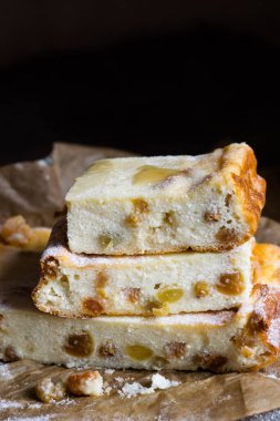 Ahşap bir masadaki kabartma kağıdının üzerinde kuru üzüm ve bal olan süzme peynir güvecine yakın çekim. Geleneksel Rus tatlı zapekankası