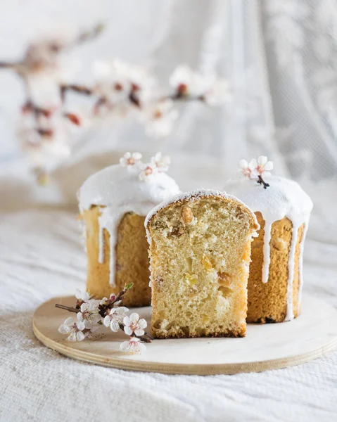 伝統的なイースターのパンやケーキ ライトリネンのテーブルクロスに白いアイシングと花で飾られました 選択的な焦点 垂直方向 イースターのコンセプト — ストック写真