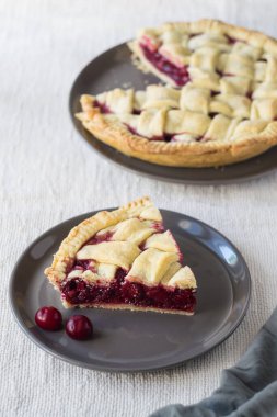 Açık keten arka planda gri tabakta vişneli pasta, seçici odak