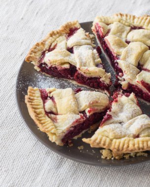 Açık keten arka planda gri tabakta kesilmiş vişneli pasta, seçici odak