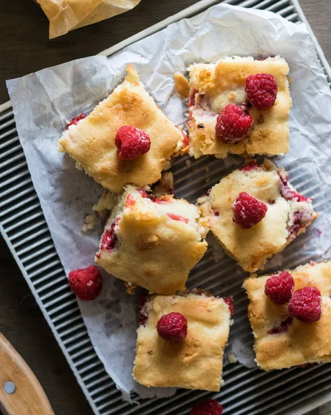 Blondie, white chocolate brownie with raspberry on a grey wooden background, top view