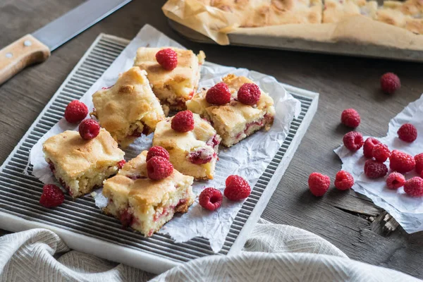 Blondie, white chocolate brownie with raspberry on a grey wooden background, selective focus