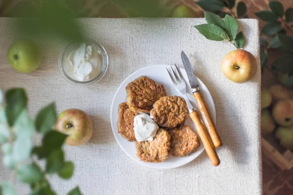 Apple fritters for breakfast. Delicious and hearty pancakes with sour cream and fresh apples. Top view