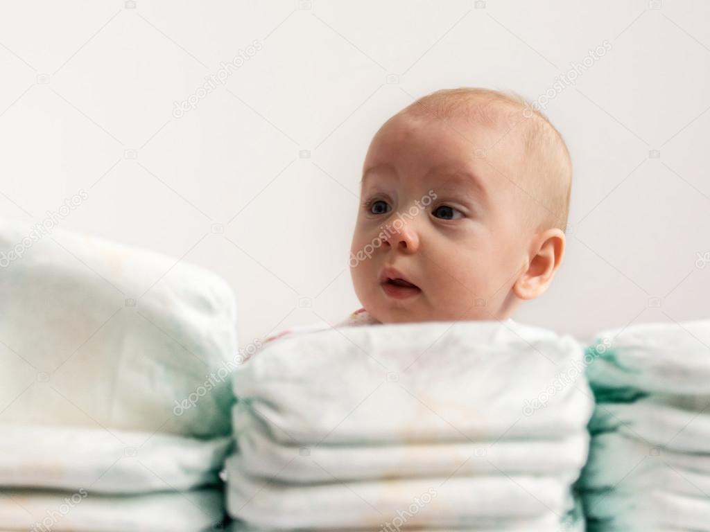 Baby looking over stack of diapers 2