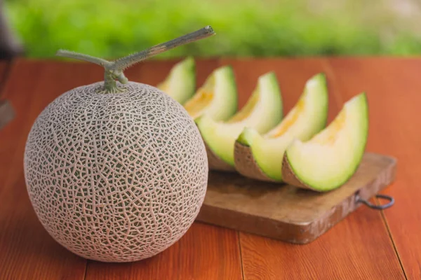 Ahşap tahtada dilimlenmiş kavun dolu bir karpuz fotoğrafı.