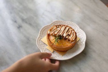 Masadaki beyaz tabakta kadın eli olan pasta. 