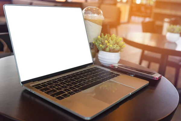 Kafedeki tahta masada dizüstü bilgisayar ve kahve fincanı.