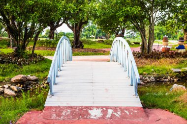 Tahta köprü ve bahçe arka planında ağaç olan renkli çiçek.