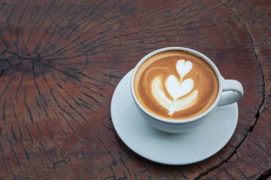 Eski ahşap arka planda kalp latte sanatıyla beyaz kahve. 