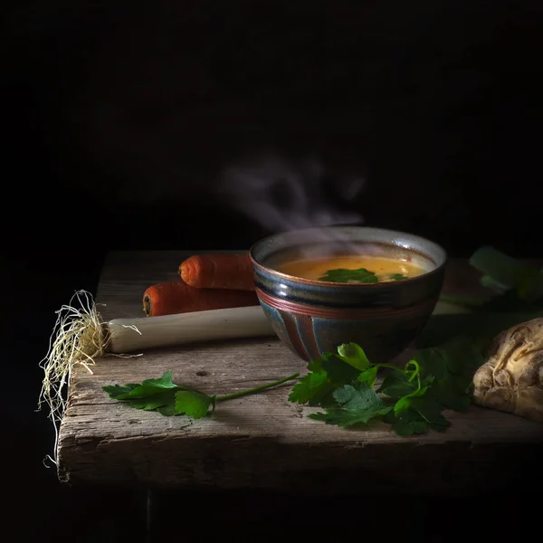 Парящий овощной суп и ингредиенты на деревенском деревянном столе — стоковое фото