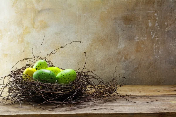 Пасхальне гніздо з зеленими кольоровими яйцями на дошках з сільського дерева — стокове фото