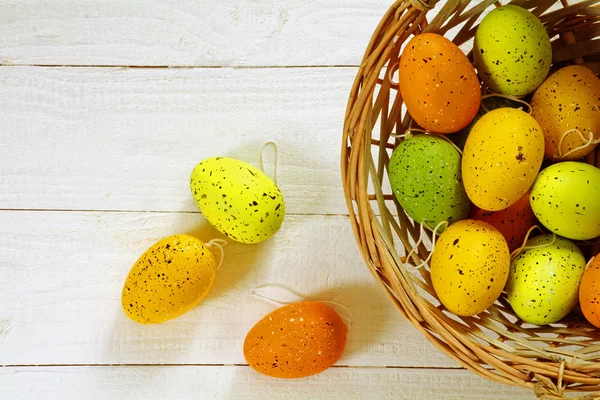 Osterhintergrund, Korb mit Eiern in grün, orange und gelb — Stockfoto