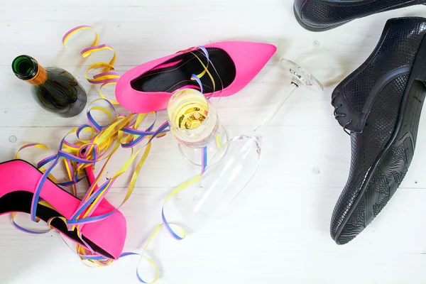 Κυρίες ροζ υψηλή heela και μαύρο mens παπούτσια που βρίσκεται μεταξύ σαμπάνια και σερπαντίνες, έννοια κόμμα — Φωτογραφία Αρχείου