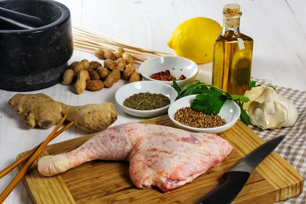 Pata de pollo crudo con ingredientes para preparar pinchos de carne a la parrilla asiáticos con salsa de maní satay —  Fotos de Stock
