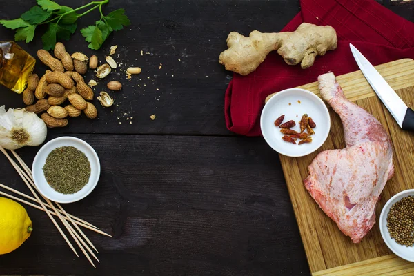 Perna de frango cru com ingredientes para satay asiático em madeira escura, vista de cima , — Fotografia de Stock