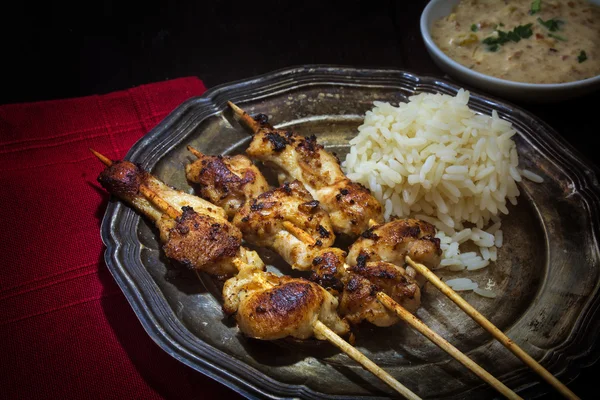 Brochetas de carne asiática con arroz y salsa de maní satay en un plato de plata —  Fotos de Stock