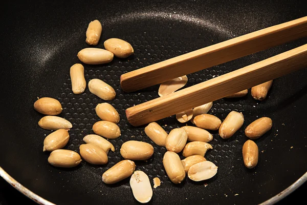 Peeled peanuts roasted in a black pan as a snack or to cook Asia satay sauce — Stock Photo, Image