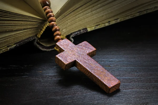 Chapelet en bois catholique avec croix dans un vieux livre sur le bois foncé — Photo