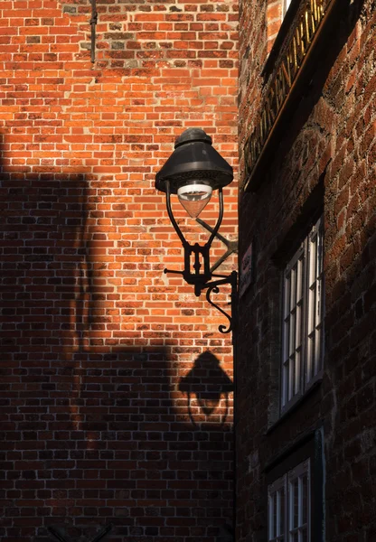 Lampadaire avec ombre entre les murs de briques historiques dans le Hans — Photo