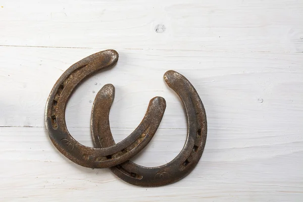 Dos viejas herraduras oxidadas sobre madera pintada de blanco, símbolo de buena suerte — Foto de Stock