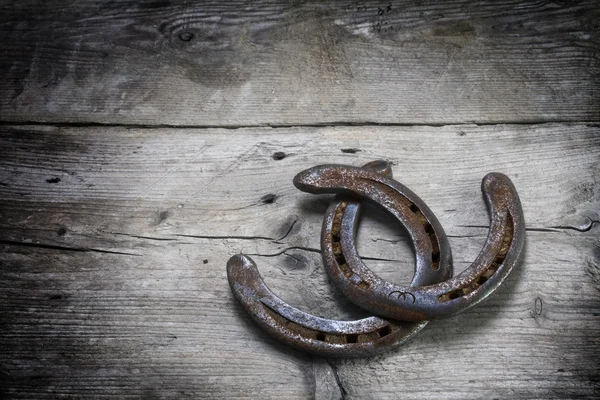 Gelukkige hoefijzers met roest met elkaar verweven op grijze rustieke houten planken — Stockfoto