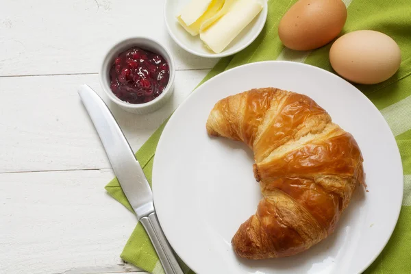 Söndagsfrukost med croissant, sylt och ägg, grön servett på vitmålade träbord, kopierings utrymme — Stockfoto