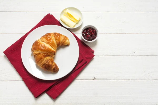 Frukost med croissant och sylt på en röd servett på vitmålat trä — Stockfoto