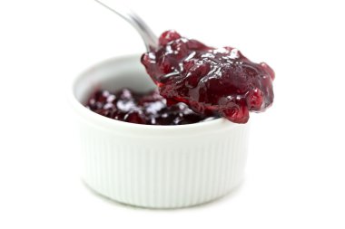 beyaz izole küçük bir kase üzerinde bir kaşık üzerinde kırmızı kızılcık reçeli