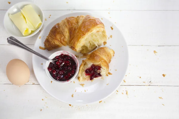 Frukost med croissant, röd frukt sylt ägg och smör på vitt trä, utsikt från ovan — Stockfoto